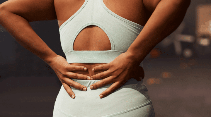 Shot of a woman experiencing back pain while working out in a gym