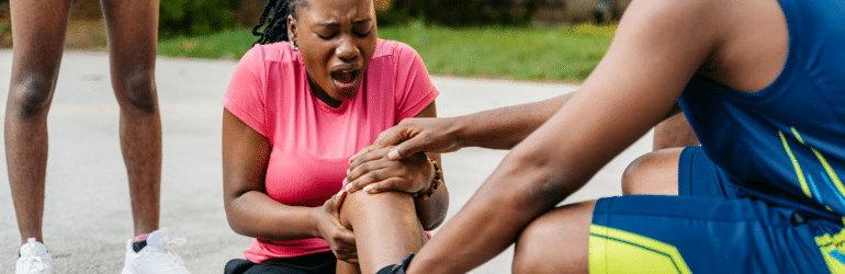 Young woman injuring her knee while playing a basketball game.